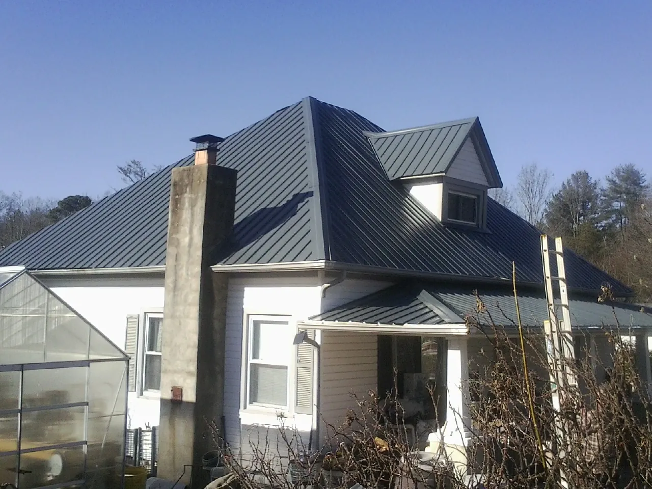 Dark blue standing seam metal roof on a white farmhouse with dormer — Slate & Tile Roof Repair by Roofing Brothers in Bakerstown