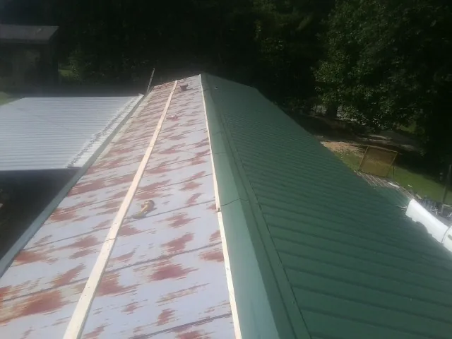 Old rusted panels beside newly installed green metal roofing — Wind Damage Roof Repair by Roofing Brothers in Bakerstown