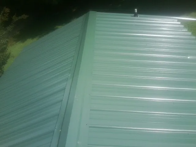 New green metal panels meeting at the ridge of a roof — Flat Roof Repair work by our crew in Bakerstown