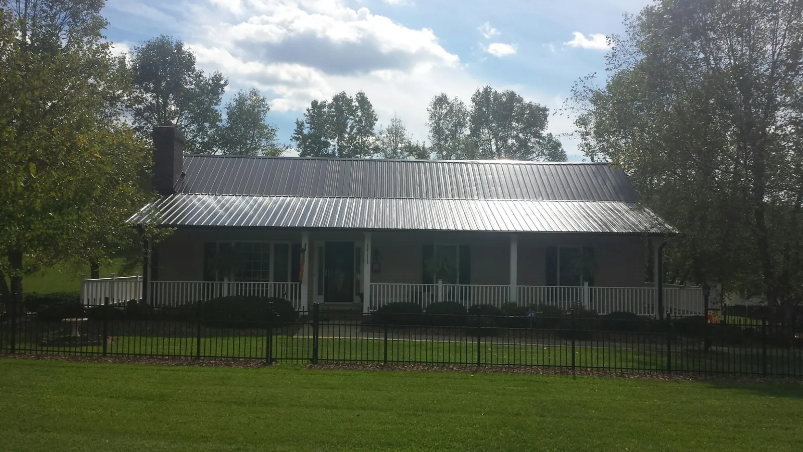 Gray metal roof on a brick ranch with a full width front porch — Gutter Guard Installation work by our crew in Bakerstown
