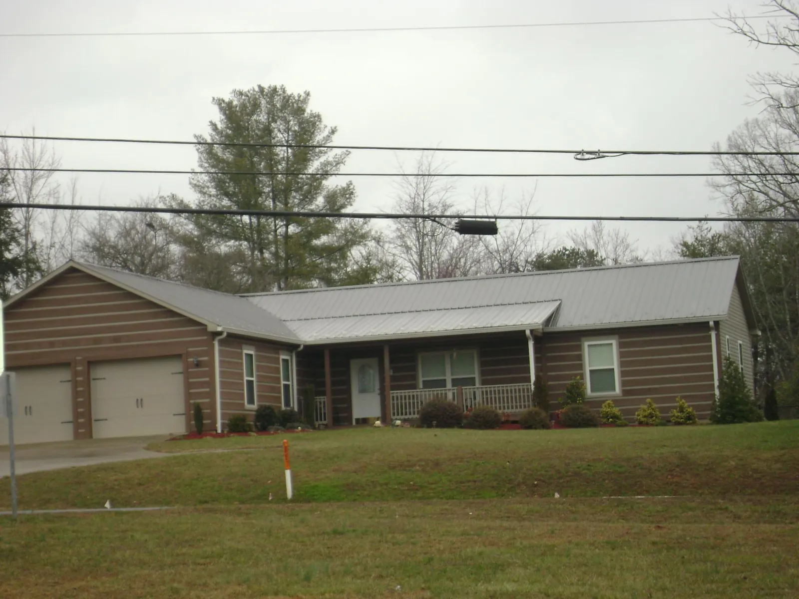 Gray metal roof on a log sided ranch home with a front porch in Bakerstown
