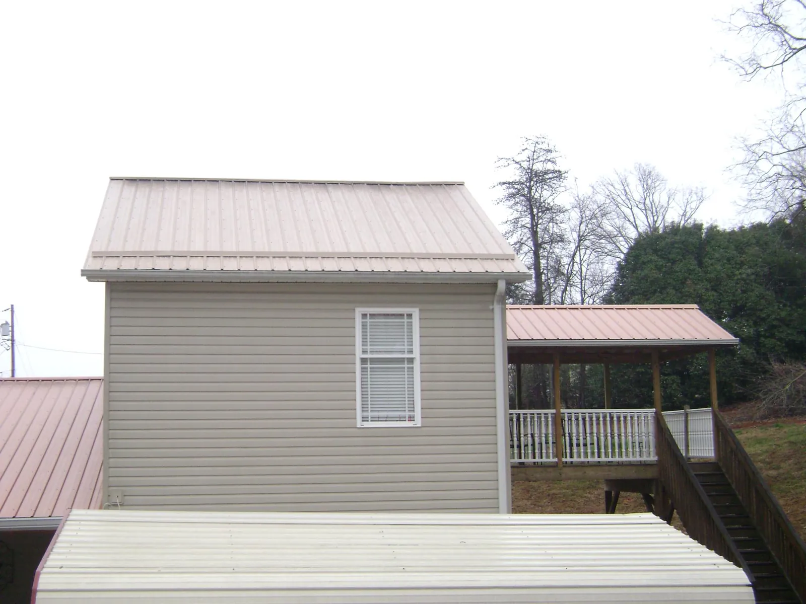 Tan metal roofs on a two story addition and attached porch, from a Roof Replacement job in Bakerstown