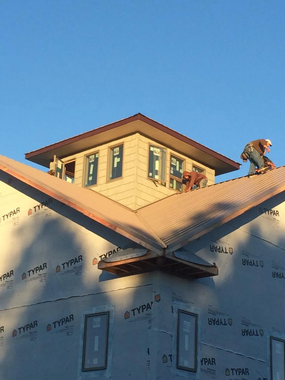Roofers working around a rooftop cupola on a new metal roof at sunset — Roof Waterproofing in Bakerstown by Roofing Brothers